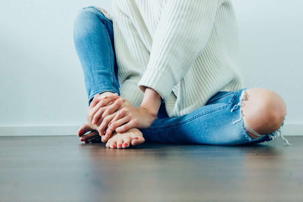 Woman sits on the floor holding her ankle