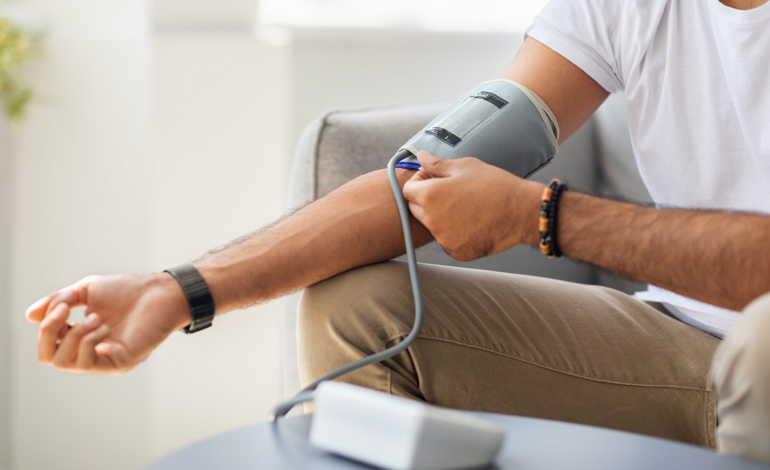 A man checks his blood pressure using an at-home monitor.