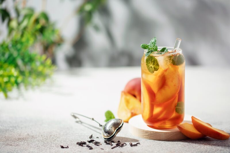 A glass of refreshing iced herbal tea with peaches and mint.