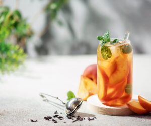 A glass of refreshing iced herbal tea with peaches and mint.