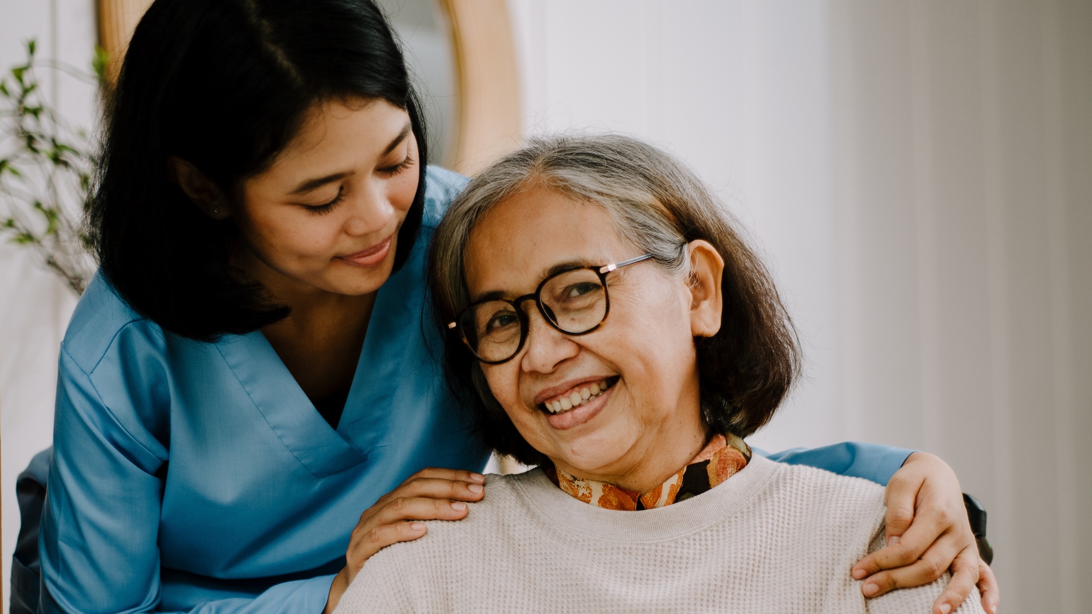 A younger woman rests her hand gently on an older woman's shoulder