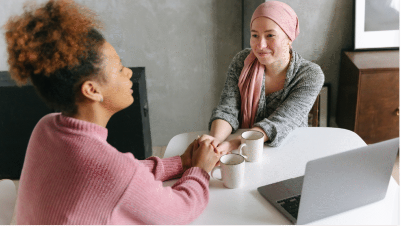 A woman comforts her friend, both drinking tea