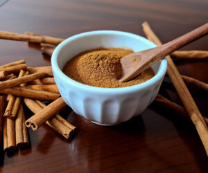 A bowl of ground cinnamon, surrounded by cinnamon sticks
