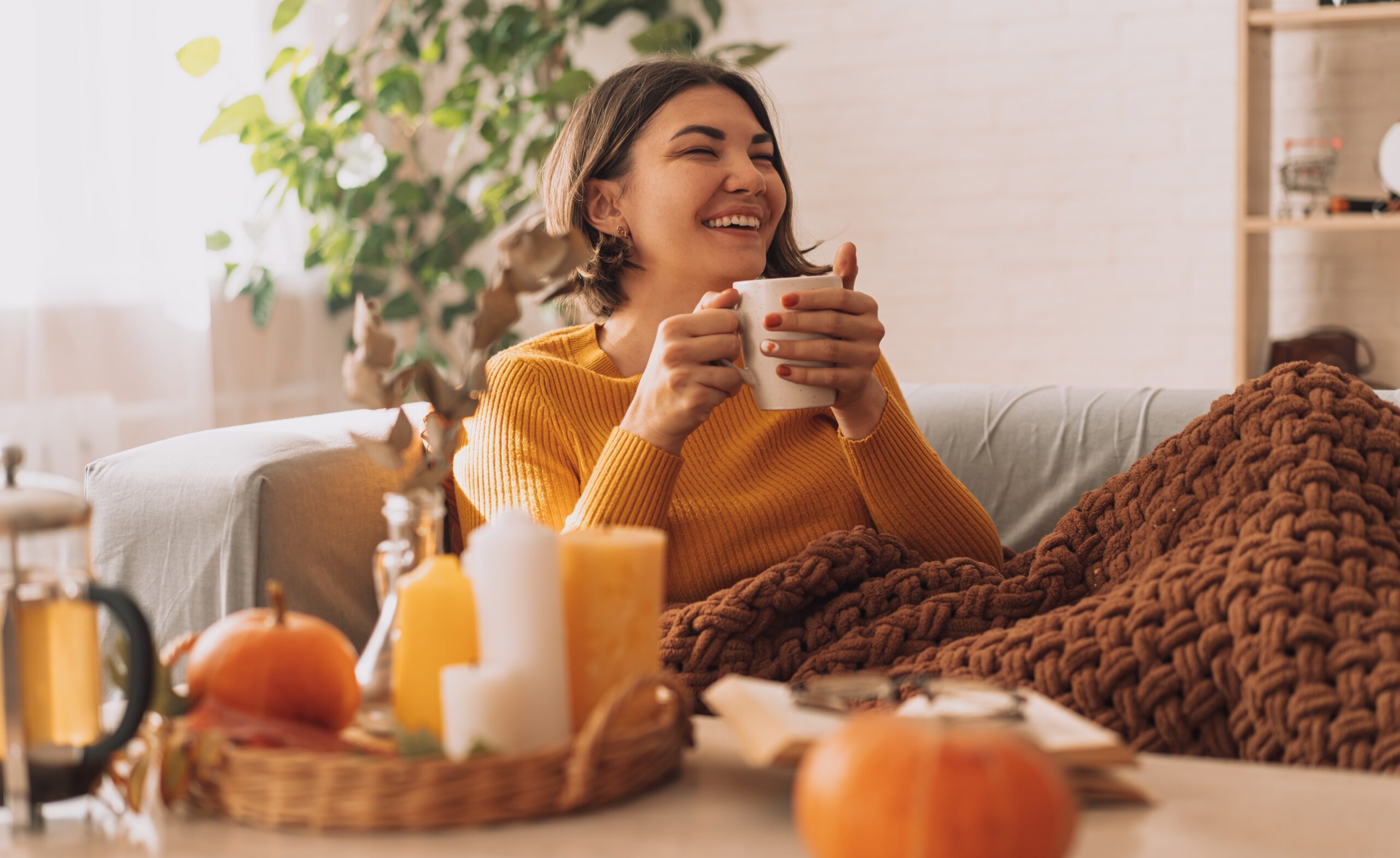 A lady sits drinking a cup of herbal tea surrounding by autumnal decor.