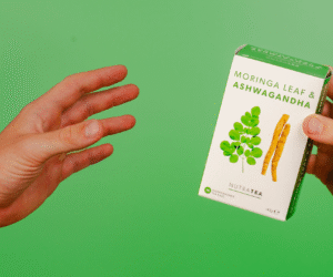 Two hands holding a box of NutraTea Moringa Leaf and Ashwagandha herbal blend tea bags