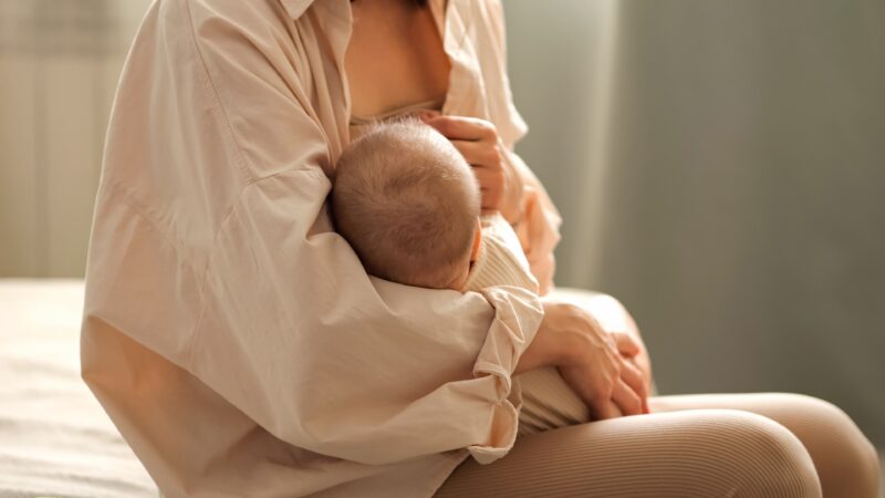 Mother enjoying a cup of fenugreek herbal tea while breastfeeding.