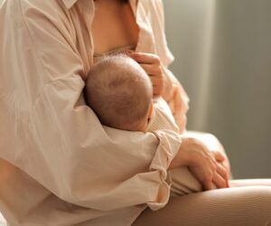 Mother enjoying a cup of fenugreek herbal tea while breastfeeding.